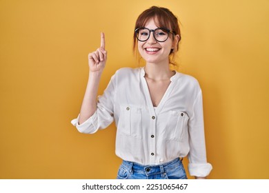 Young beautiful woman wearing casual shirt over yellow background pointing finger up with successful idea. exited and happy. number one.  - Powered by Shutterstock