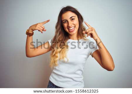 Young beautiful woman wearing casual white t-shirt over isolated background smiling pointing to head with both hands finger, great idea or thought, good memory