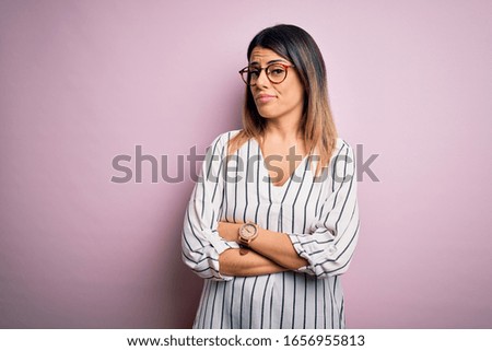 Young beautiful woman wearing casual striped t-shirt and glasses over pink background looking sleepy and tired, exhausted for fatigue and hangover, lazy eyes in the morning.