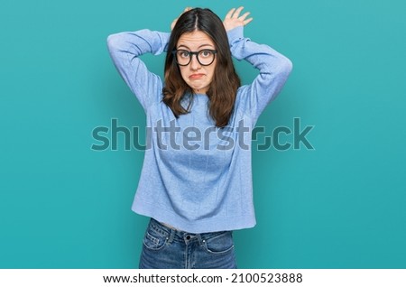Young beautiful woman wearing casual clothes and glasses doing bunny ears gesture with hands palms looking cynical and skeptical. easter rabbit concept. 