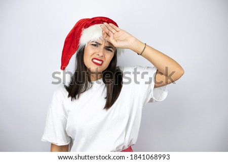 Young beautiful woman wearing a christmas hat over white background Touching forehead for illness and fever, flu and cold, virus sick
