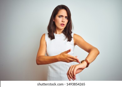 Young beautiful woman wearing dress standing over white isolated background In hurry pointing to watch time, impatience, upset and angry for deadline delay