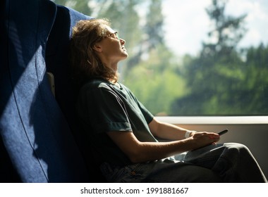 Young beautiful woman wearing glasses sitting in high-speed train relaxing while traveling