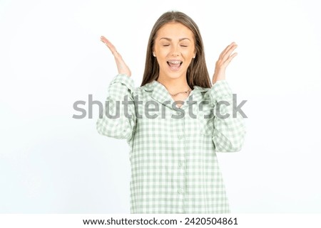 Young beautiful woman wearing green plaid pyjama goes crazy as head goes around feels stressed because of horrible situation