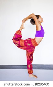 Young Beautiful Woman Wearing Harem Pants Indoors, Practicing A Yoga Pose (dancer's Pose)