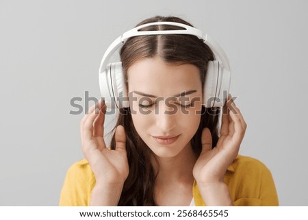 Young beautiful woman wearing headphones and listening to music with eyes closed