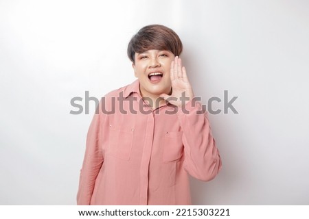 Young beautiful woman wearing a pink shirt shouting and screaming loud with a hand on her mouth. communication concept.