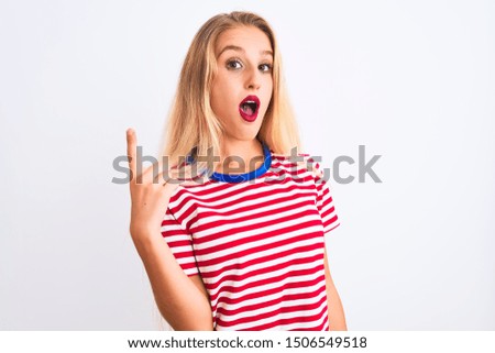 Young beautiful woman wearing red striped t-shirt standing over isolated white background pointing finger up with successful idea. Exited and happy. Number one.