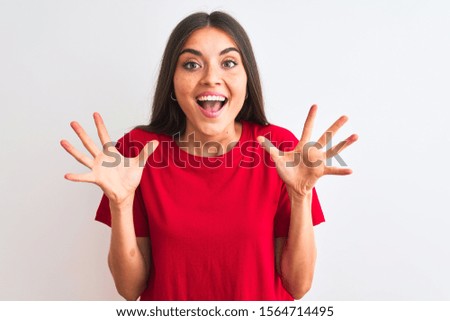 Young beautiful woman wearing red casual t-shirt standing over isolated white background celebrating crazy and amazed for success with arms raised and open eyes screaming excited. Winner concept
