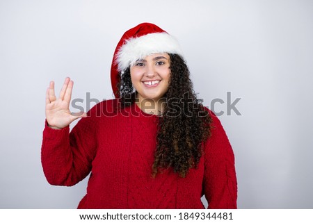 Young beautiful woman wearing a Santa hat over white background doing hand symbol