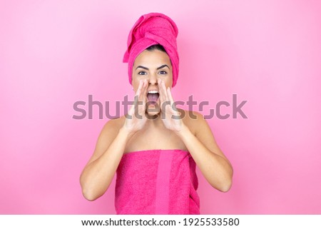 Young beautiful woman wearing shower towel after bath standing over isolated pink background shouting and screaming loud to side with hands on mouth
