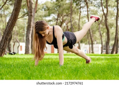 Young Beautiful Woman Wearing Sportive Clothes On City Park, Outdoors Woman Doing Push Ups With One Leg Up. Outdoor Sports, Healthy Life Concepts.