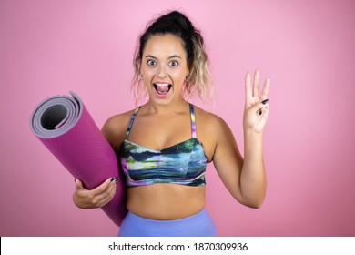 Young Beautiful Woman Wearing Sportswear And Holding A Splinter Over Isolated Pink Background Showing And Pointing Up With Fingers Number Three While Smiling Confident And Happy