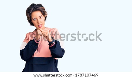 Young beautiful woman wearing sportswear ready to fight with fist defense gesture, angry and upset face, afraid of problem 
