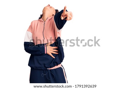 Young beautiful woman wearing sportswear laughing at you, pointing finger to the camera with hand over body, shame expression 