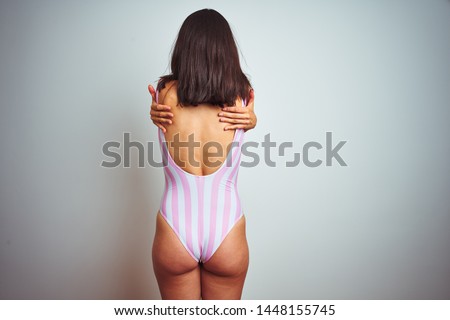 Young beautiful woman wearing striped pink swimsuit swimwear over isolated background Hugging oneself happy and positive from backwards. Self love and self care