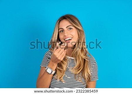 Young beautiful woman wearing striped t-shirt  holding an invisible aligner ready to use it. Dental healthcare and confidence concept.