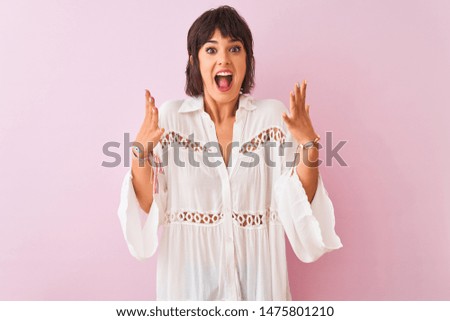 Young beautiful woman wearing summer white shirt standing over isolated pink background celebrating crazy and amazed for success with arms raised and open eyes screaming excited. Winner concept