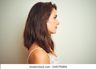 Young beautiful woman wearing t-shirt standing over white isolated background looking to side, relax profile pose with natural face with confident smile.