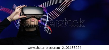 Young beautiful woman wearing a VR headset and experiencing a virtual reality simulation, metaverse and cyberspace concept