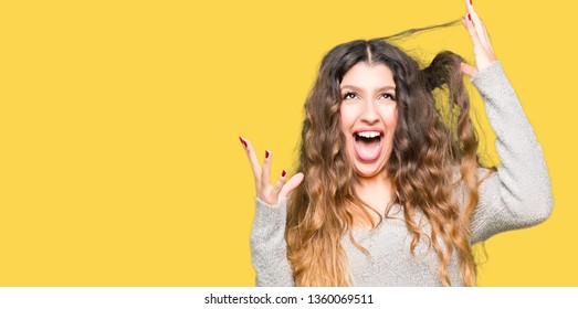 Young beautiful woman wearing winter dress celebrating mad and crazy for success with arms raised and closed eyes screaming excited. Winner concept - Shutterstock ID 1360069511