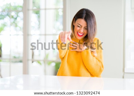 Young beautiful woman wearing winter sweater at home Laughing of you, pointing to the camera with finger hand over chest, shame expression