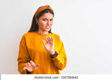 Young beautiful woman wearing yellow sweater and diadem over isolated white background disgusted expression, displeased and fearful doing disgust face because aversion reaction. With hands raised. 