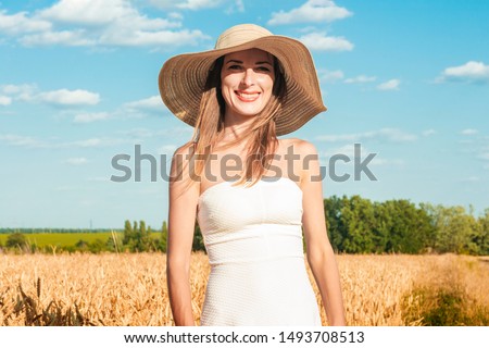 Young beautiful woman in a white dress and a hat on a milf's field. The concept of outdoor recreation, a trip to the village