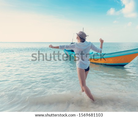 Young beautiful woman in a white shirt and sunglasses enjoys a vacation in Thailand, on the seashore against the background of a traditional Thai boat, sea travel and tours to tropical islands.