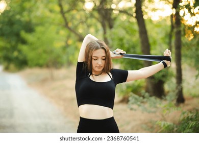 Young beautiful woman working out with fitness rubber bands in the forest, girl training hands on nature, sport concept - Shutterstock ID 2368760541