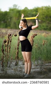 Young beautiful woman working out with fitness rubber bands in field of dry sunflowers, girl training hands, sport concept - Shutterstock ID 2368760581