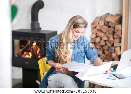 Young beautiful woman works on computer from a home with a laptop on a white desk as a freelancer