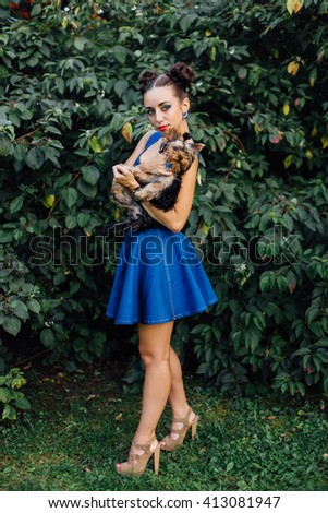 Young beautiful woman with Yorkshire Terrier near green bush 