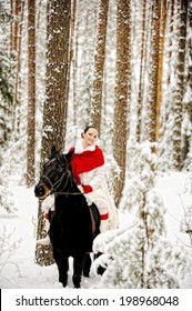 Young beautiful woman/princess riding black horse at white winter forest.  