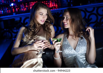 Young beautiful women, have a rest on a sofa and drink beverages