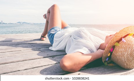 Young Beautiful Women Laying Down On The Wooden Ground Along The Beach. Women Relax Along The Beach On The Holiday.