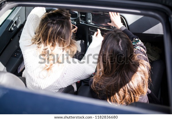 Young and beautiful women singing\
and dancing to the rhythm of music in their car, aerial\
view