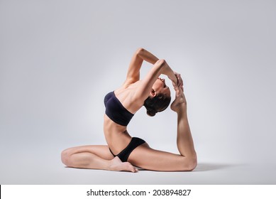 young beautiful yoga posing on a gray studio background