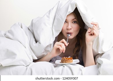 young beauty girl on diet eating spoon instead of dessert  under white cover on white background - Powered by Shutterstock