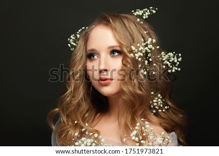 Young beauty. Pretty woman with blonde hair and flowers on black background