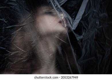 Young beauty sad woman trapped behind a plastic sheet as protection against COVID-19. Nicely fits for book cover 