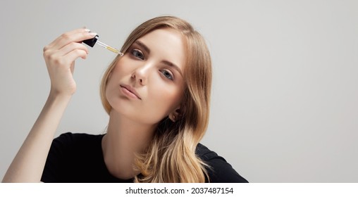 Young Beauty Woman Applying Argan Castor Oil Onto Hair At Home, Grey Background.