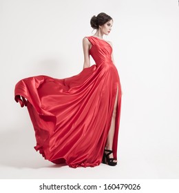 Young Beauty Woman In Fluttering Red Dress. White Background.