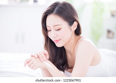 Young beauty woman lying and applying hand cream at home