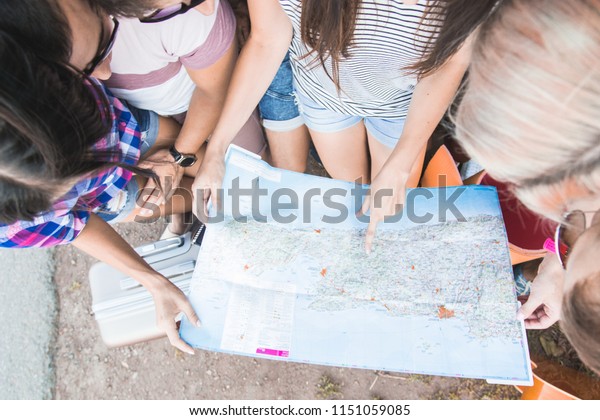 The young best friends with suitcases on a trip
by car. They sit in the back of the car, they look at the map,
resting after a long drive and having fun. Hitchhiking and car
trips with friends