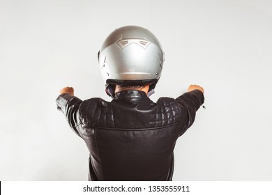 Young Biker From Back In A Leather Jacket Pretending To Ride A Motorcycle Isolated On White Background