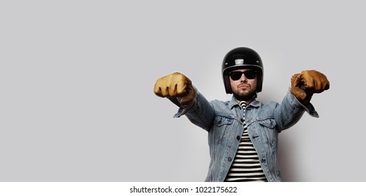 Young Biker In A Blue Denim Jacket Pretending To Ride A Motorcycle Isolated On White Background. Horizontal. Wide