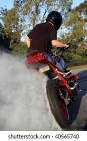 Young biker doing a doughnut on his motorcycle and making lots of smoke