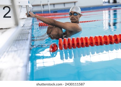 Young biracial male athlete swimmer prepares for a swim at an indoor pool.  His focused expression captures the determination of an athlete in training. - Powered by Shutterstock