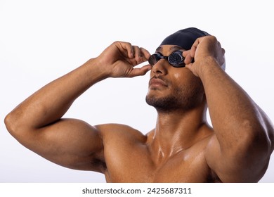 Young biracial male swimmer adjusts his swimming goggles. Captured in a studio setting, he's preparing for a swim or competition. - Powered by Shutterstock